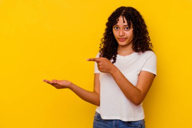 Sarı arka planda izole edilmiş genç melez bir kadın. Elinde bir kopyası olduğu için heyecanlı..