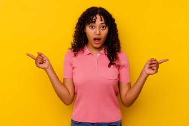 Sarı arka planda izole edilmiş genç bir ırk kadını farklı kopya alanlarını gösteriyor, birini seçiyor, parmaklarıyla gösteriyor..