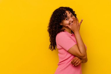 Sarı arka planda soyutlanmış genç melez bir kadın. Gülüyor, kaygısız, doğal duygular içinde..