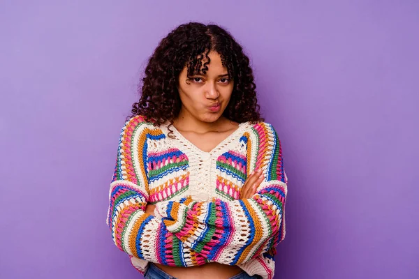 Mor arka planda soyutlanmış melez bir kadın hoşnutsuzca kaşlarını çatmış, kollarını kavuşturmuş..