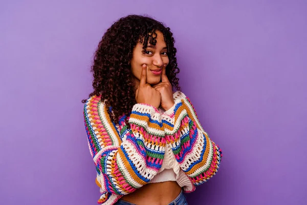 Mor arka planda izole edilmiş genç melez kadın iki seçenek arasında kuşkulanıyor.