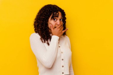 Genç melez kadın sarı arka planda izole edilmiş korkmuş ve korkmuş..