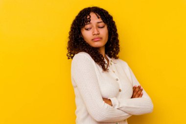 Sarı arka planda izole edilmiş genç melez kadın tekrarlanan bir görevden yoruldu..