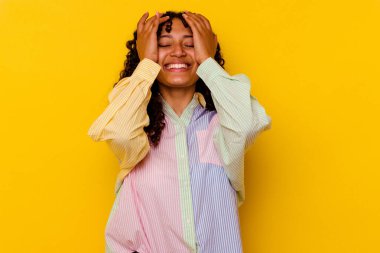 Sarı arka planda soyutlanmış melez bir kadın ellerini başının üstünde tutarak neşeyle gülüyor. Mutluluk kavramı.