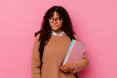 Pembe arka planda soyutlanmış, kafası karışmış, kuşkulu ve kendinden emin olmayan genç bir kız öğrenci..