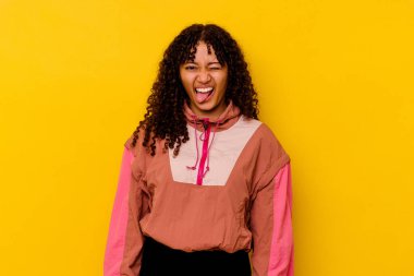 Genç melez kadın pembe arka planda izole edilmiş komik ve dost canlısı bir dil uzatıyor..