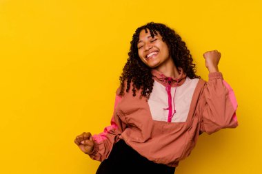 Genç melez kadın pembe arka planda izole edilmiş dans ediyor ve eğleniyor..