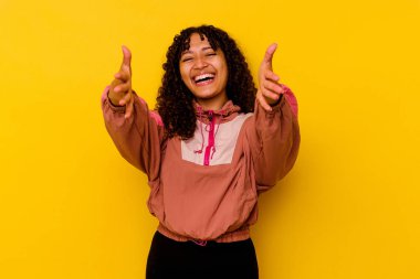 Pembe arka planda soyutlanmış genç melez bir kadın kameraya sarılıyor..