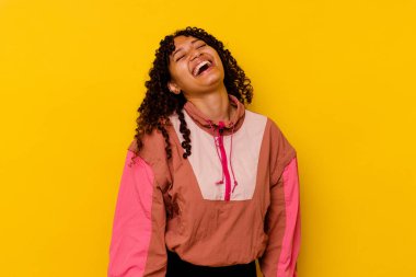 Genç melez bir kadın pembe arka planda izole edilmiş rahat ve mutlu bir şekilde gülüyor, boynunda dişlerini gösteriyor..