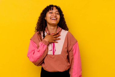 Pembe arka planda soyutlanmış genç bir ırk kadını yüksek sesle gülüyor elini göğsünde tutuyor..