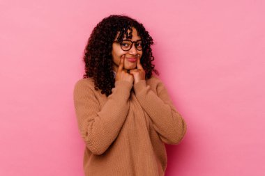 Pembe arka planda izole edilmiş genç melez kadın iki seçenek arasında kuşkulanıyor.