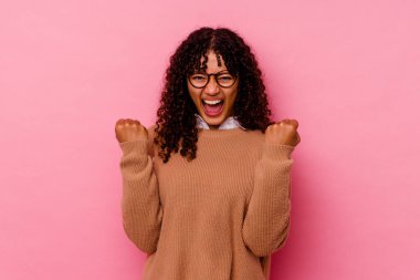 Pembe arka planda soyutlanmış, tasasız ve heyecanlı genç bir ırk kadını. Zafer konsepti.