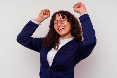 Beyaz arka planda soyutlanmış genç iş kadını özel bir günü kutluyor, kollarını enerji ile kaldırıyor..