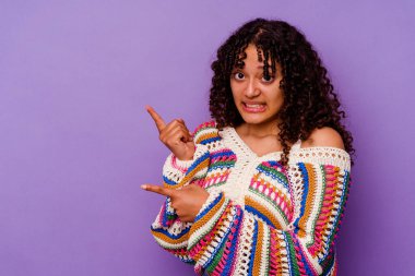 Mor arka planda izole edilmiş genç melez kadın işaret parmağıyla fotokopi alanını işaret ederek şok oldu..