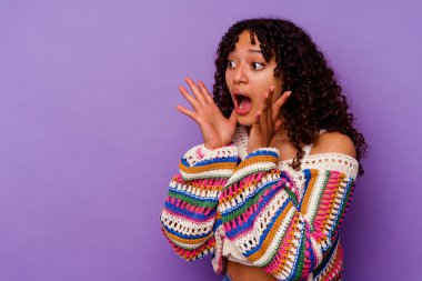 Mor arka planda soyutlanmış genç melez kadın yüksek sesle bağırıyor, gözleri açık ve elleri gergin tutuyor..