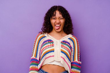 Mor arka planda izole edilmiş genç bir ırk kadını. Komik ve dost canlısı bir dil uzatıyor..