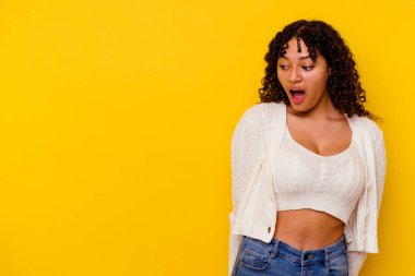 Sarı arka planda izole edilmiş genç bir ırk kadını gördüğü bir şey yüzünden şoka uğruyor..