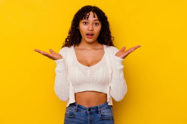 Sarı arka planda yaşayan genç melez kadın şaşırdı ve şok oldu..