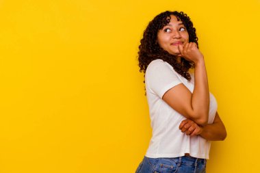 Sarı arka planda izole edilmiş genç bir ırk kadını rahat bir şekilde fotokopi odasına bakan bir şeyi düşünüyor..