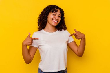 Sarı arka planda izole edilmiş genç melez kadın parmakları aşağıda, olumlu hisler içinde..