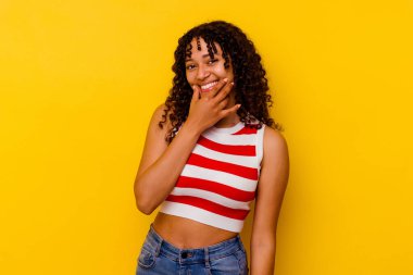 Genç melez kadın sarı arka planda izole edilmiş, iki seçenek arasında kuşkulanıyor..