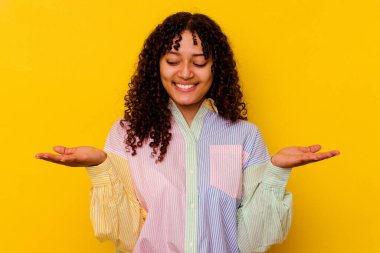 Sarı arka planda izole edilmiş genç bir ırk kadını elinde avuç içi bir şeyle kameraya sunuyor..