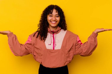 Pembe arka planda soyutlanmış genç melez kadın kollarıyla ölçeği yapıyor, mutlu ve kendinden emin hissediyor..