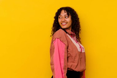 Pembe arka planda soyutlanmış genç melez bir kadın. Gülümsüyor, neşeli ve keyifli görünüyor..