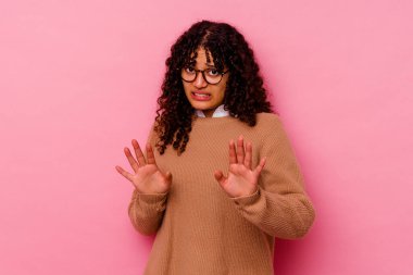 Pembe arka planda izole edilmiş genç bir ırk kadını, tiksinti gösteren birini reddediyor..