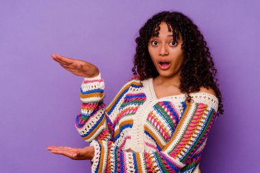 Mor arka planda izole edilmiş genç bir ırk kadını elleri arasında bir kopya alanı tutarken şok ve hayret içinde..