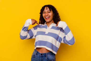 Sarı arka planda izole edilmiş genç bir ırk kadını parmağını göstererek şaşırdı ve gülümsedi..