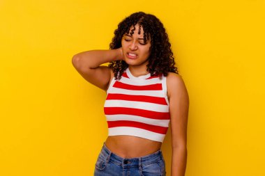 Sarı arka planda soyutlanmış genç melez bir kadın yorgun ve uykulu bir şekilde ellerini başının üstünde tutuyor..