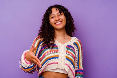 Mor arka planda izole edilmiş genç bir ırk kadını selamlama jesti olarak kameraya elini uzatıyor..