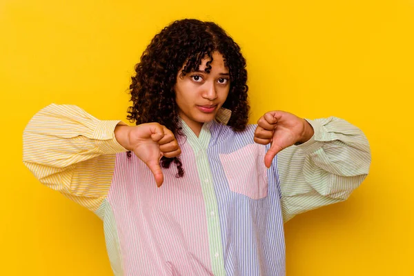親指を示す黄色の背景に隔離された若い混合人種の女性 失望の概念 — ストック写真