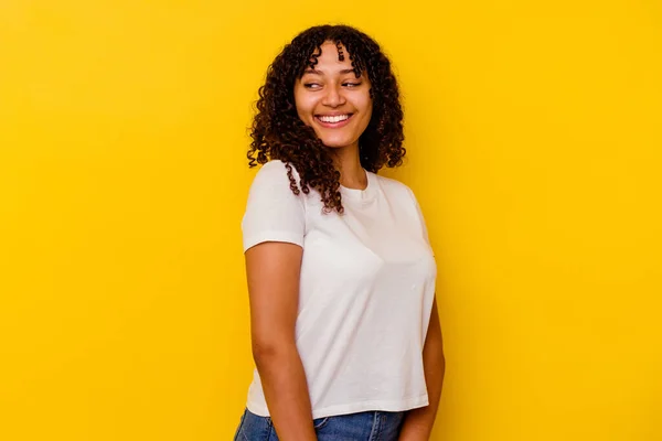 Joven Mujer Mestiza Aislada Sobre Fondo Amarillo Mira Lado Sonriente — Foto de Stock