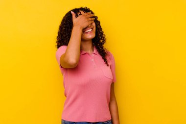 Sarı arka planda soyutlanmış melez bir kadın ellerini başının üstünde tutarak neşeyle gülüyor. Mutluluk kavramı.