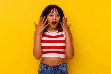 Sarı arka planda izole edilmiş genç melez kadın on numarayı elleriyle gösteriyor..