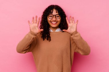 Pembe arka planda izole edilmiş genç melez kadın on numarayı elleriyle gösteriyor..