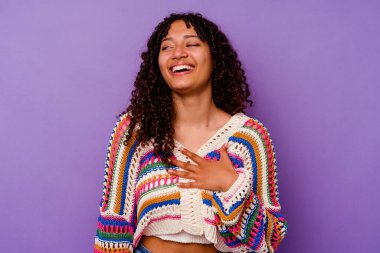 Mor arka planda soyutlanmış genç bir ırk kadını yüksek sesle gülüyor ve elini göğsüne koyuyor..