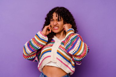 Mor arka planda izole edilmiş genç bir ırk kadını kulaklarını elleriyle kapatıyor..