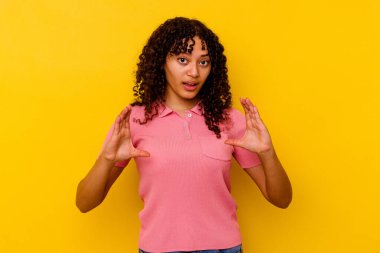 Sarı arka planda izole edilmiş genç bir ırk kadını elinde avuç içi bir şeyle kameraya sunuyor..