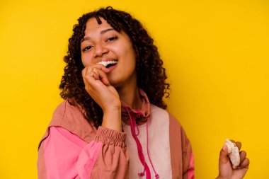 Sarı arka planda izole edilmiş pirinç keki yiyen genç bir ırk sporcusu.