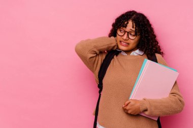 Genç öğrenci melez kadın pembe arka planda izole edilmiş kafasının arkasına dokunuyor, düşünüyor ve bir seçim yapıyor..