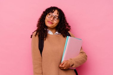 Genç öğrenci ırk kadını pembe arka planda izole edilmiş hedeflere ve amaçlara ulaşma hayali kuruyor.