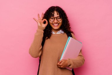 Genç öğrenci melez kadın pembe arka planda izole edilmiş neşeli ve kendinden emin..
