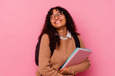 Genç öğrenci melez kadın pembe arka planda izole edilmiş gülüyor ve eğleniyor..