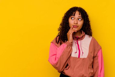 Pembe arka planda izole edilmiş genç melez kadın şüpheli ve şüpheci bir ifadeyle yana bakıyor..