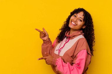 Pembe arka planda izole edilmiş genç melez bir kadın işaret parmağıyla işaret ederek heyecanlanıyor..