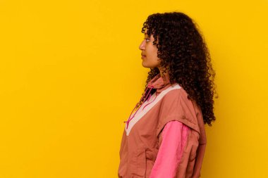 Genç melez kadın pembe arka planda izole edilmiş, sola bakıyor, yandan poz veriyor.