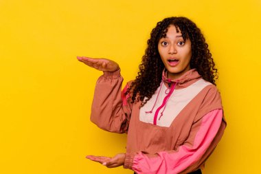 Pembe arka planda izole edilmiş genç bir ırk kadını elleri arasında bir kopya alanı tutarken şok ve hayret içinde..